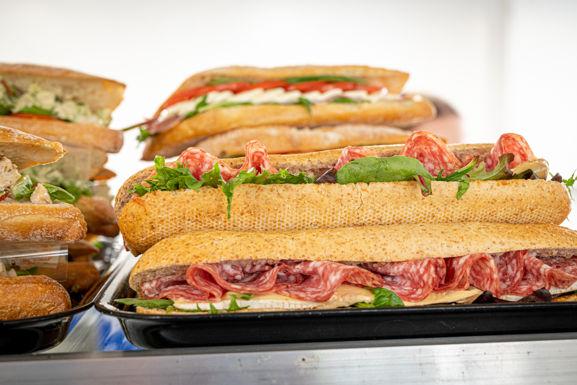 Fresh artisan baguettes with various fillings including salami and vegetables