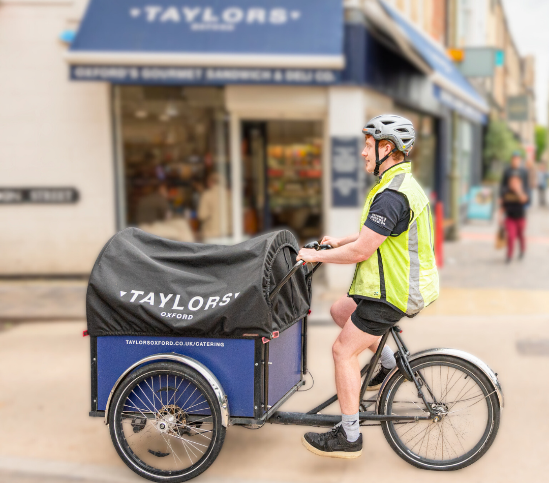 Taylors Oxford delivery cyclist with cargo bike outside the shop